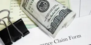 Healthcare underpayments represented by a claim form and a hundred dollar bill