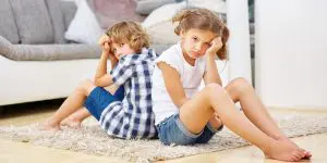 Two unhappy children sitting back to back, emphasizing the importance of following these tips for divorcing parents